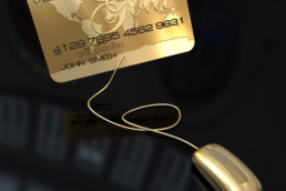 A gold credit card connected to a golden computer mouse on a black background