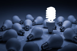 Lit energy saving lightbulb amongst unlit incandescent bulbs